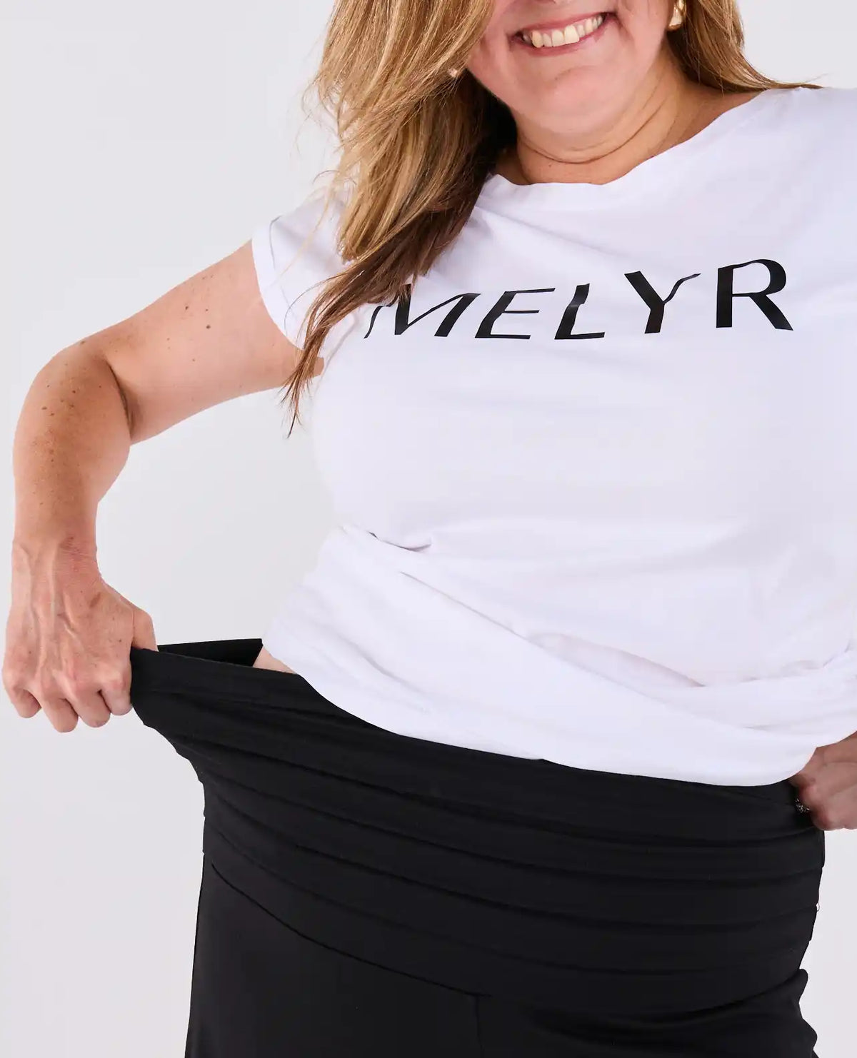 Amy stretching the pleated MELYRFLEX waistband of black Ravello trousers