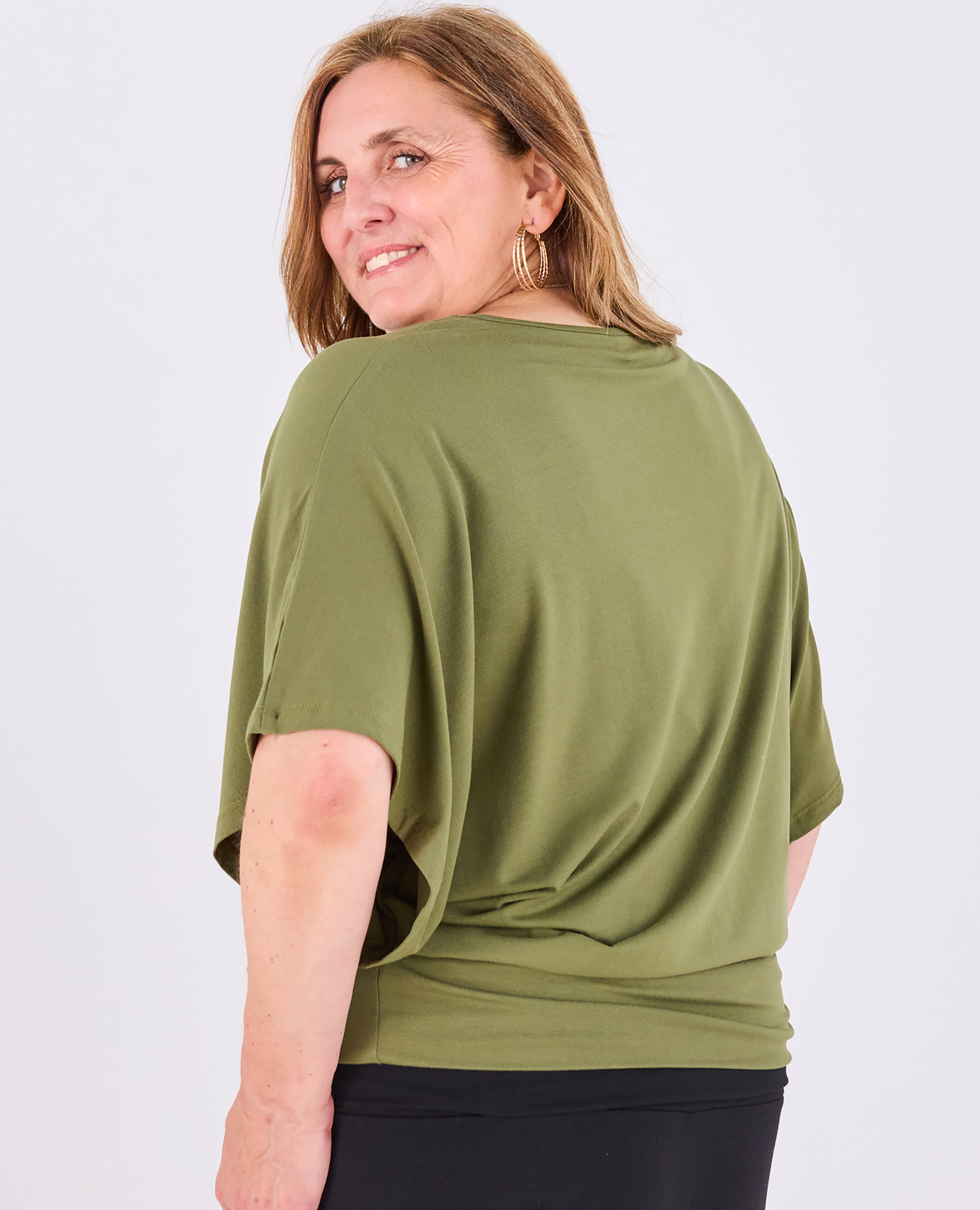 A plus size woman wearing a Melyr olive green short-sleeve Nico top, shown from the back against a light grey studio background.
