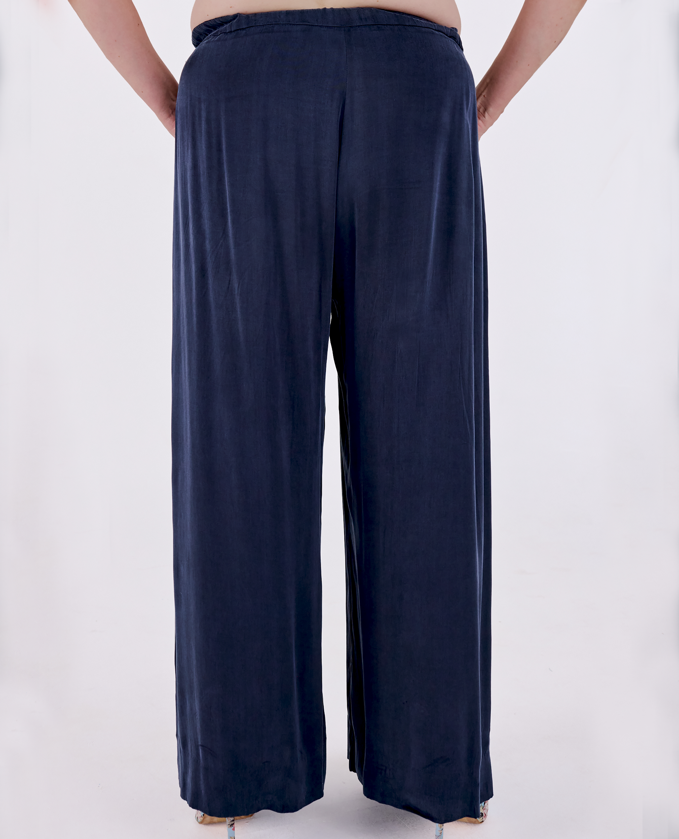 A plus size woman shown from the back wearing Melyr Portofino, wide-leg navy pants against a plain light background.