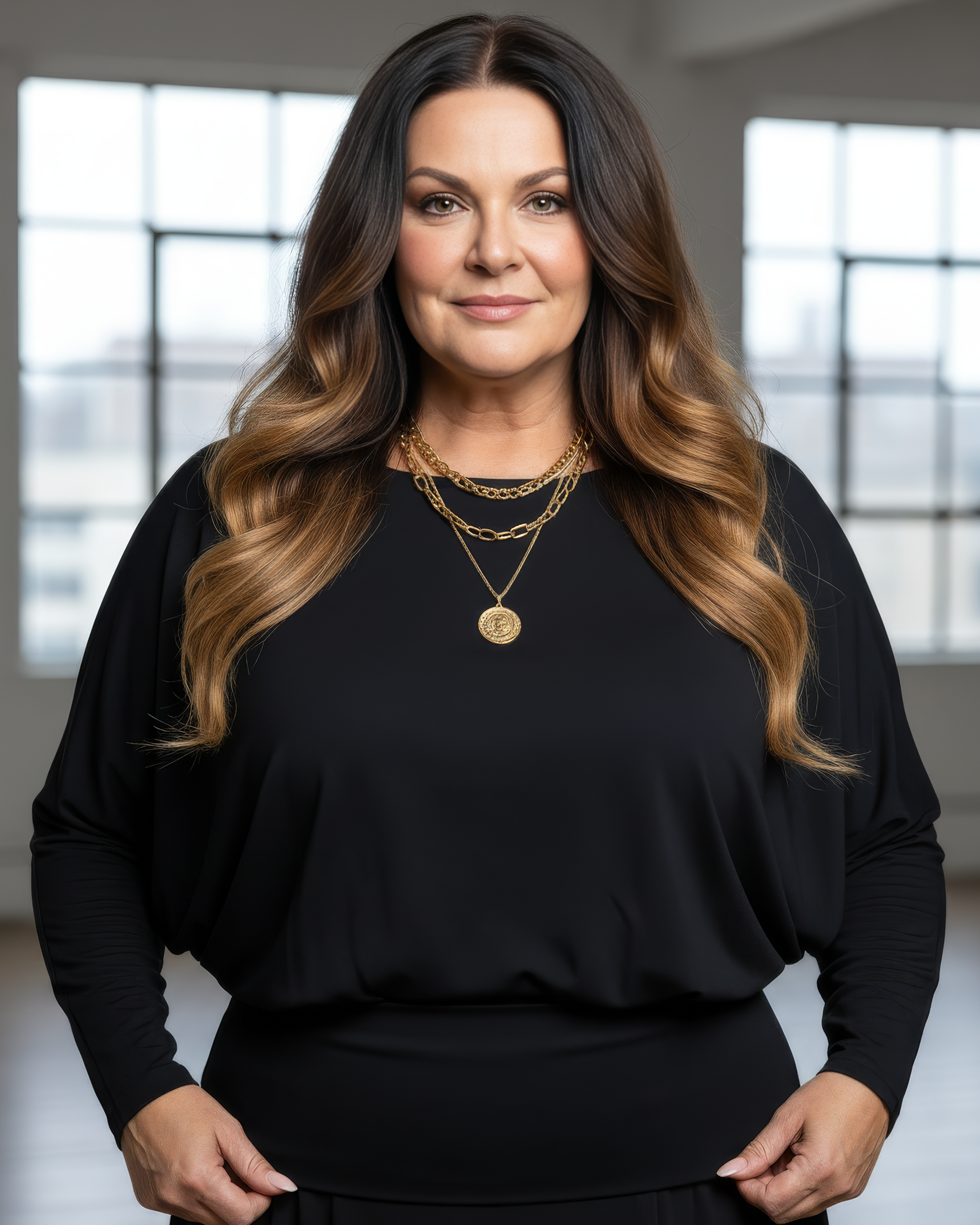 Woman wearing a black top and gold jewelry in a well-lit room