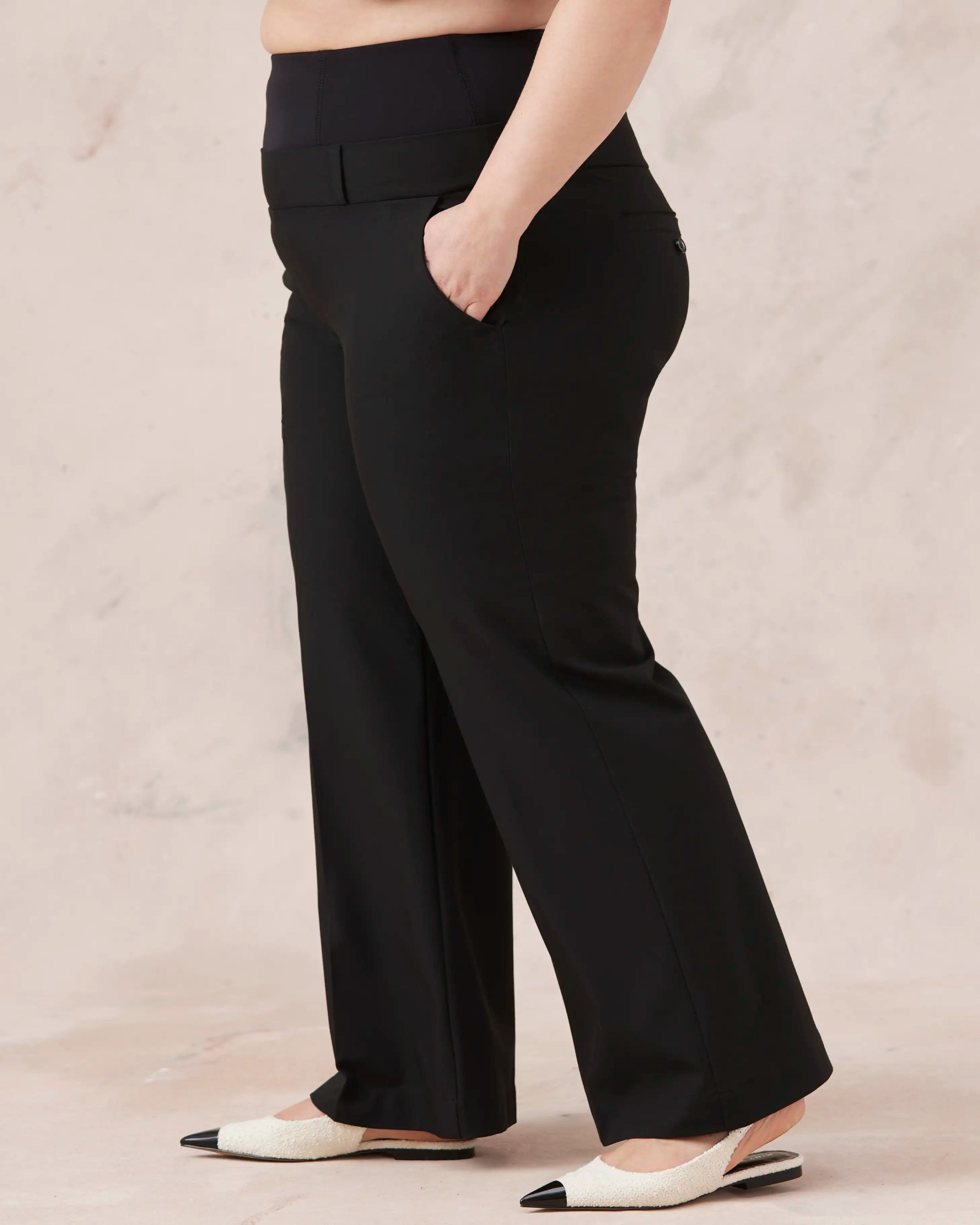 Plus-size model wearing black wide-leg melyr pants on a beige background