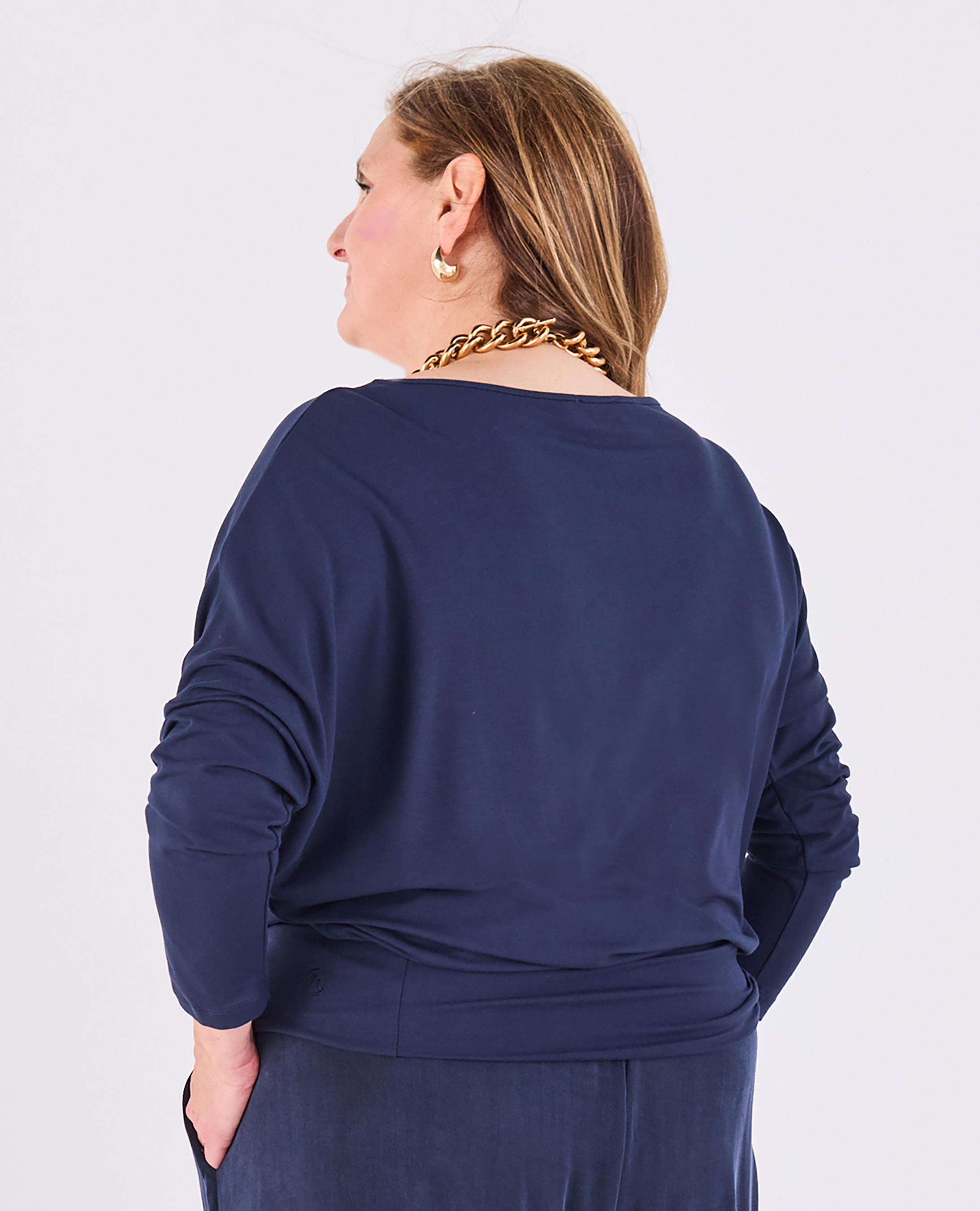 A woman shown from the back wearing a Melyr Aimee navy batwing long-sleeve top and matching bottoms, photographed against a light grey studio background.