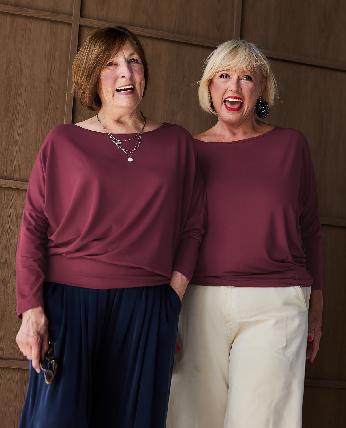 Two women with arms raised in navy Aimee tops, the hip band still in place