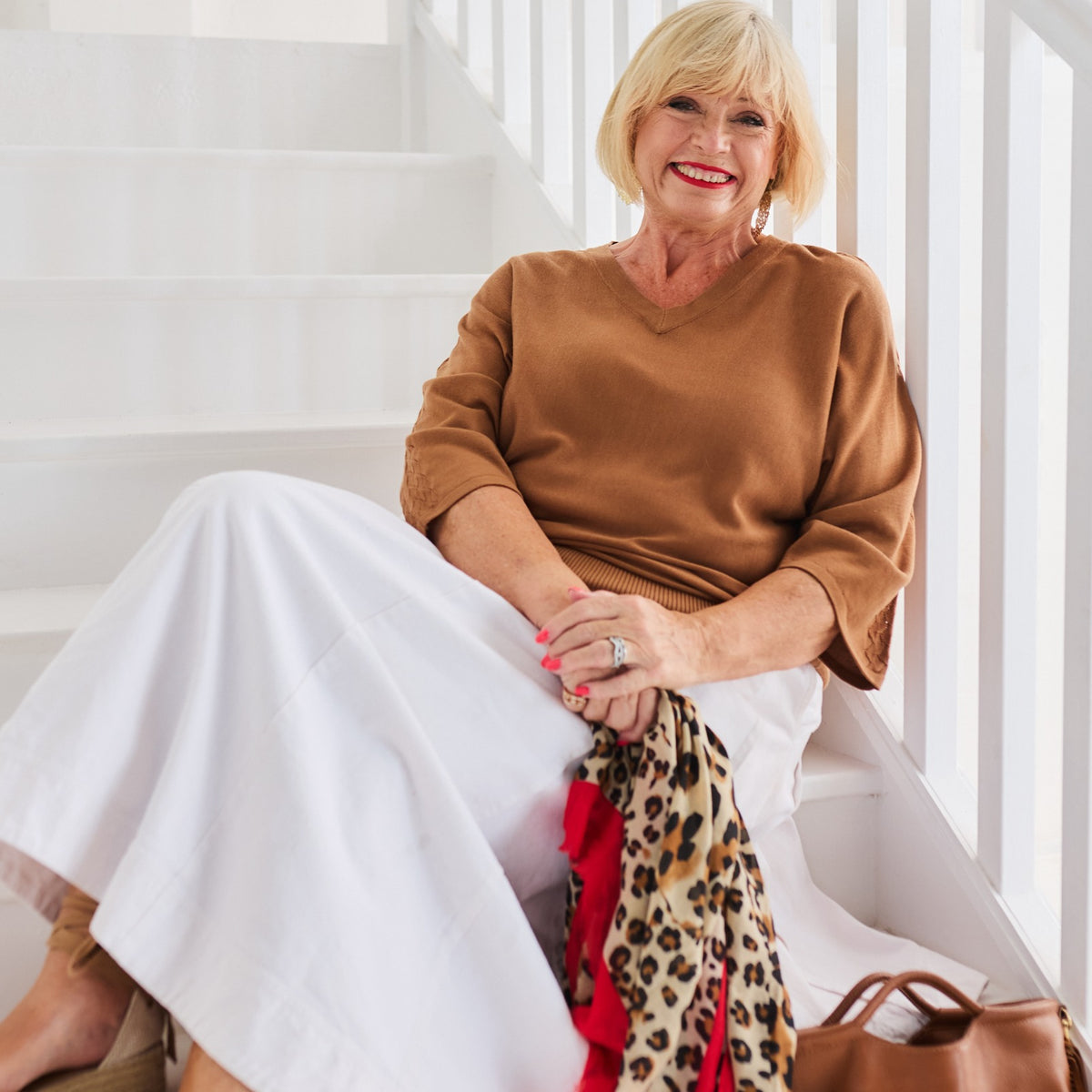 A woman in a camel MELYR knit and white trousers