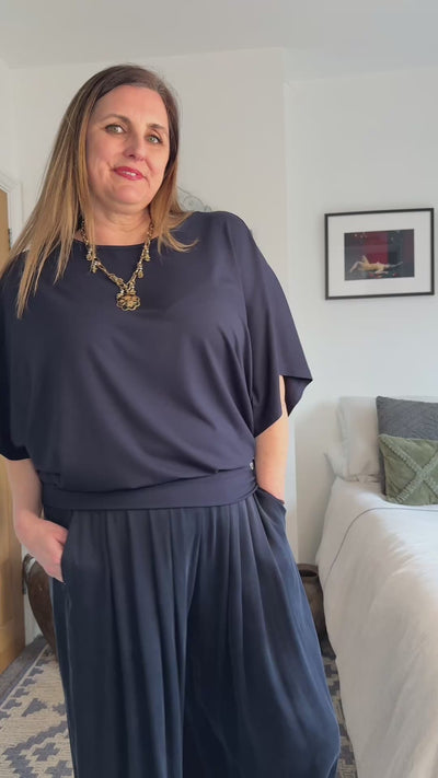 Video of woman showing a navy melyr top in a bedroom