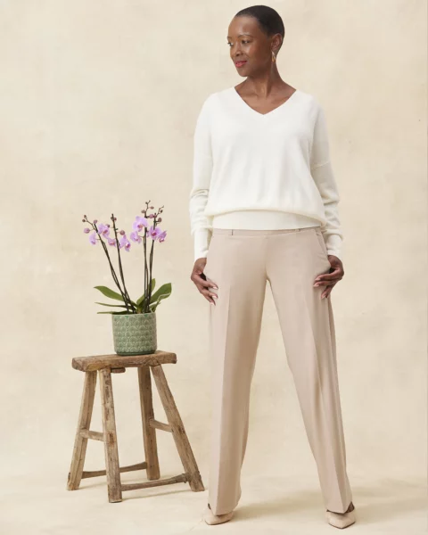 Model wears camel high waisted stretch trousers from MELYRFLEX with a white v neck knit